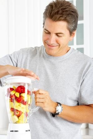 Happy man juicing his natural testosterone booster with a regular blender
